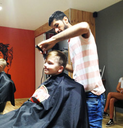 Hussein, an Iraqi refugee is shown working in his new job as a barber.